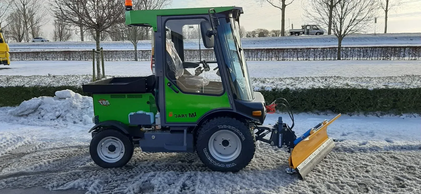 LM Trac equipped with a snowplough, clearing snow from a frosty road.